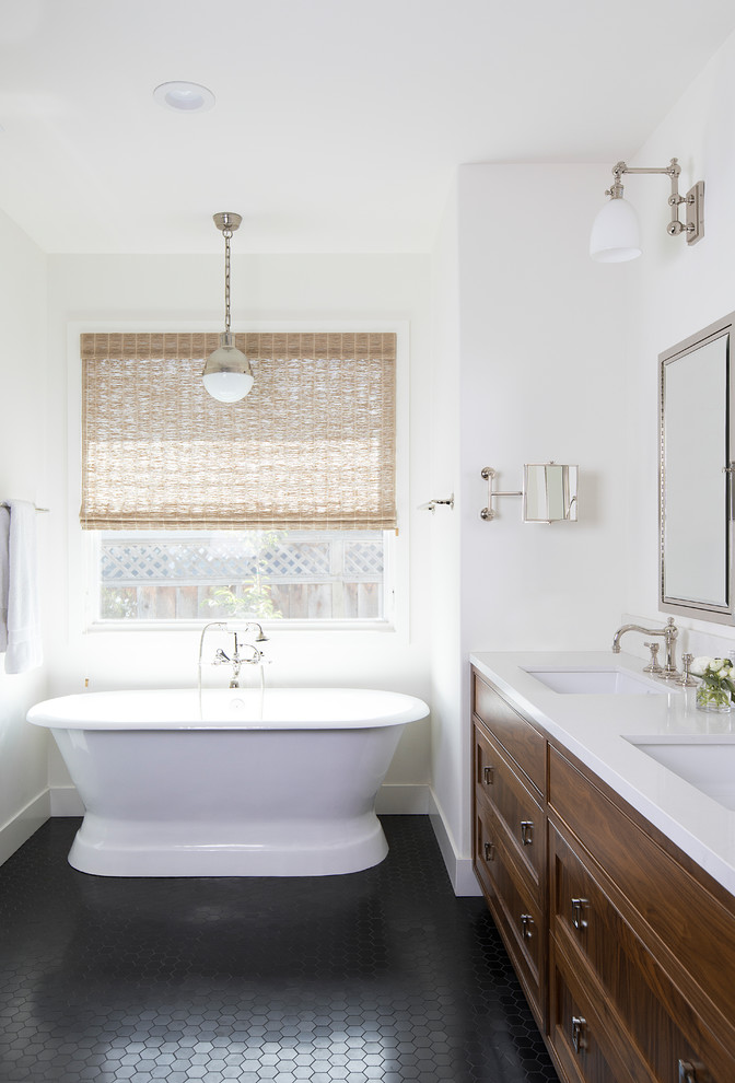 Design ideas for a transitional master bathroom in San Francisco with shaker cabinets, medium wood cabinets, a freestanding tub, white walls, an undermount sink, black floor and white benchtops.