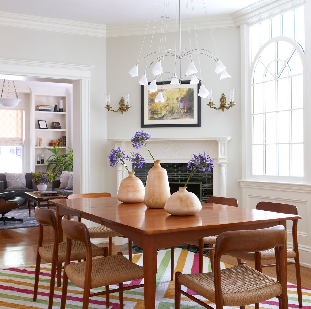 Photo of a large traditional separate dining room in Boston with white walls, medium hardwood floors, a standard fireplace, a tile fireplace surround and brown floor.