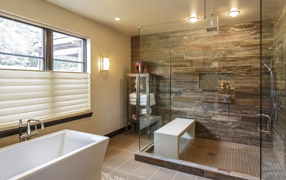 This is an example of a country master bathroom in Los Angeles with a freestanding tub, a corner shower, brown tile, white walls, grey floor and a hinged shower door.