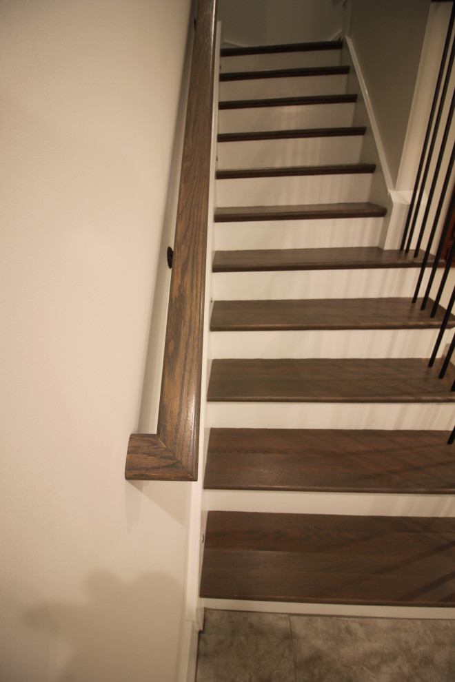 Large transitional wood l-shaped staircase in DC Metro with painted wood risers, metal railing and panelled walls.