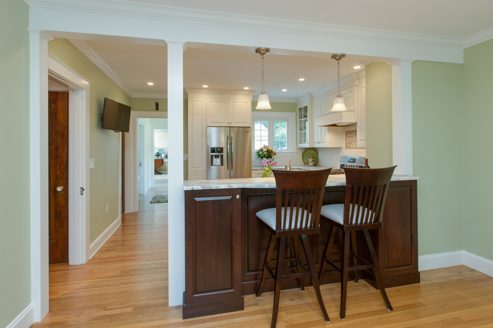 Transitional u-shaped medium tone wood floor eat-in kitchen photo in Boston with an undermount sink, raised-panel cabinets, white cabinets, granite countertops, white backsplash, subway tile backsplash and stainless steel appliances