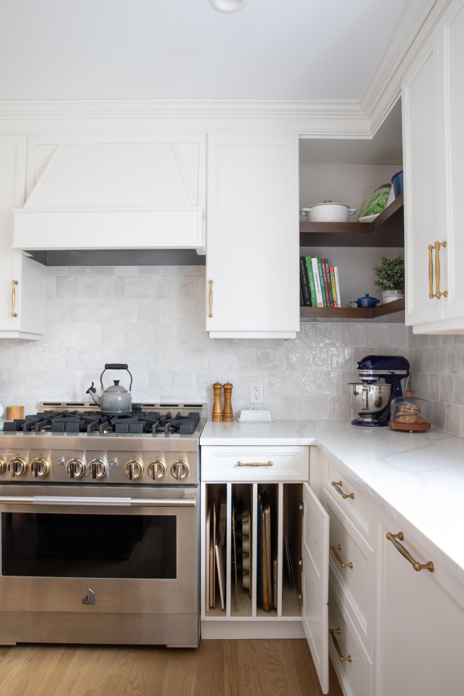 This is an example of a large transitional u-shaped eat-in kitchen in New York with a farmhouse sink, shaker cabinets, white cabinets, quartz benchtops, white splashback, ceramic splashback, panelled appliances, light hardwood floors, with island, brown floor and white benchtop.