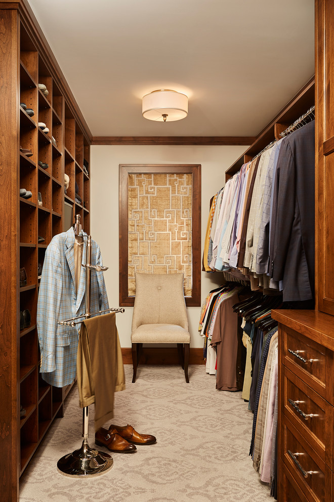 This is an example of a traditional men's dressing room in Minneapolis with recessed-panel cabinets, medium wood cabinets, carpet and beige floor.