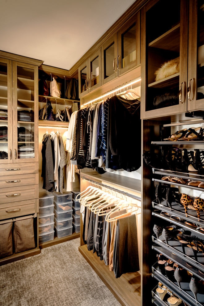 This is an example of a transitional women's walk-in wardrobe in Other with glass-front cabinets, carpet, grey floor and dark wood cabinets.
