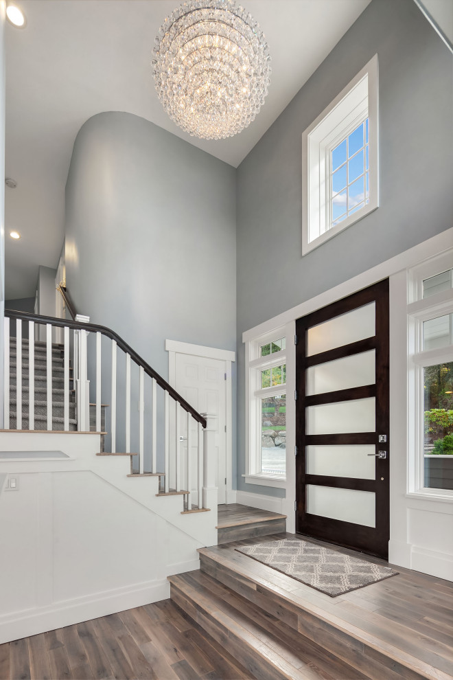 Inspiration for a large transitional foyer in Seattle with blue walls, light hardwood floors, a single front door, a dark wood front door, grey floor, exposed beam and decorative wall panelling.