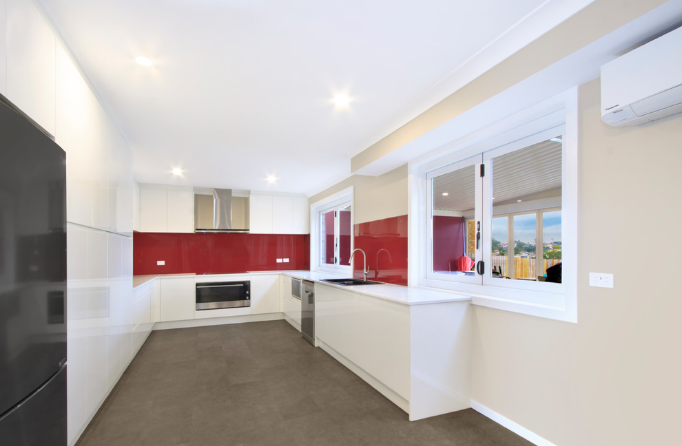 Inspiration for a modern u-shaped eat-in kitchen in Wollongong with a drop-in sink, flat-panel cabinets, white cabinets, quartz benchtops, red splashback, glass sheet splashback, stainless steel appliances, vinyl floors, grey floor and white benchtop.