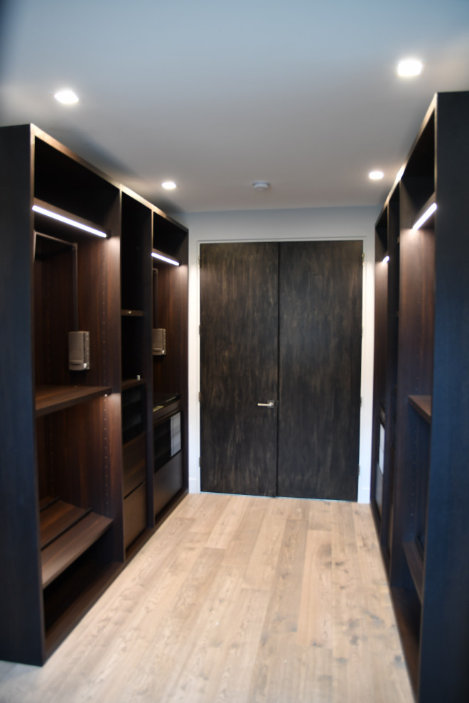 Inspiration for a mid-sized contemporary gender-neutral storage and wardrobe in DC Metro with flat-panel cabinets, dark wood cabinets, medium hardwood floors and beige floor.
