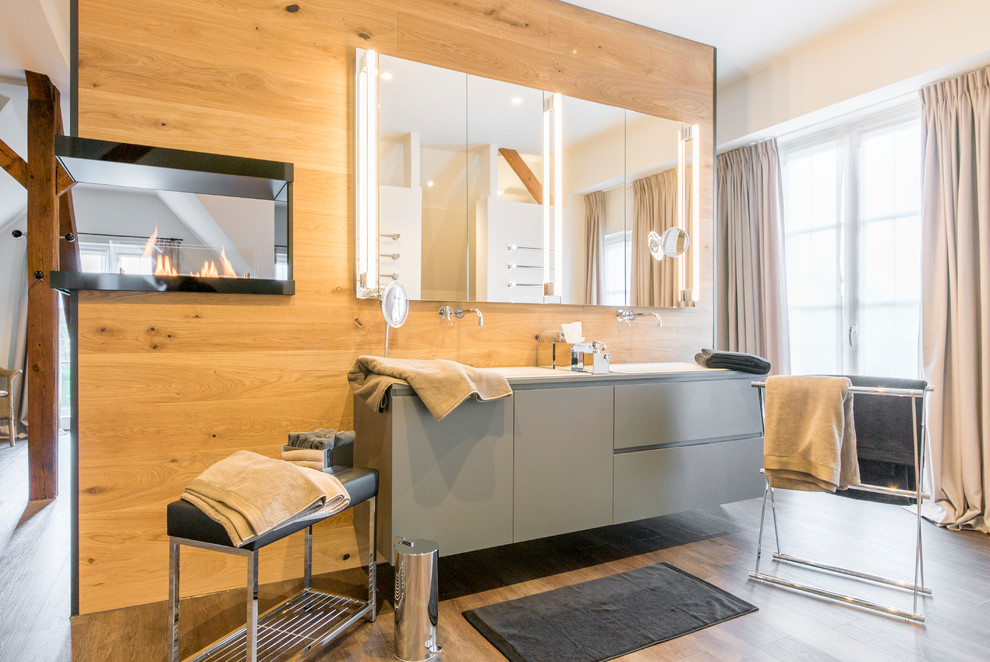 This is an example of a large eclectic 3/4 bathroom in Hanover with flat-panel cabinets, grey cabinets, a drop-in tub, a wall-mount toilet, white walls, medium hardwood floors and a drop-in sink.