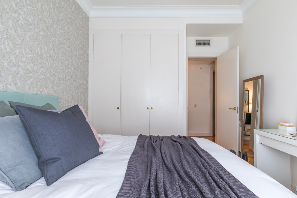 Aménagement d'une petite chambre parentale moderne avec un mur blanc, un sol en bois brun, un sol marron et du papier peint.