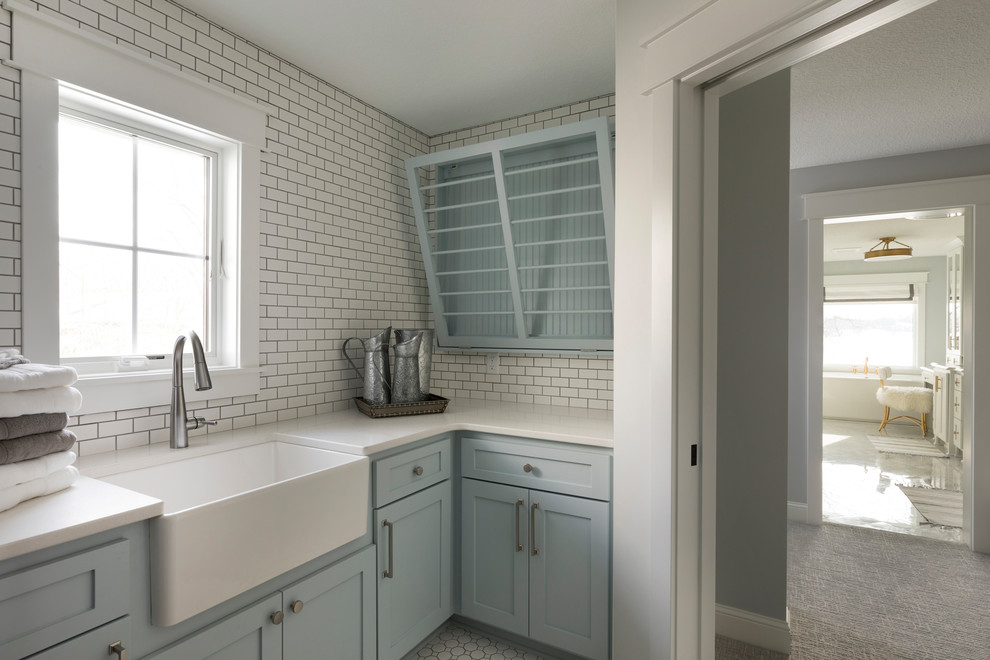 Large transitional l-shaped utility room in Minneapolis with a farmhouse sink, blue cabinets, quartz benchtops, white walls, ceramic floors, white floor, white benchtop and shaker cabinets.