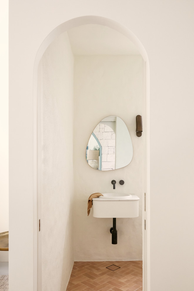 Immagine di un bagno di servizio mediterraneo con pareti bianche, pavimento in gres porcellanato, lavabo sottopiano, top in marmo, pavimento marrone e mobile bagno sospeso