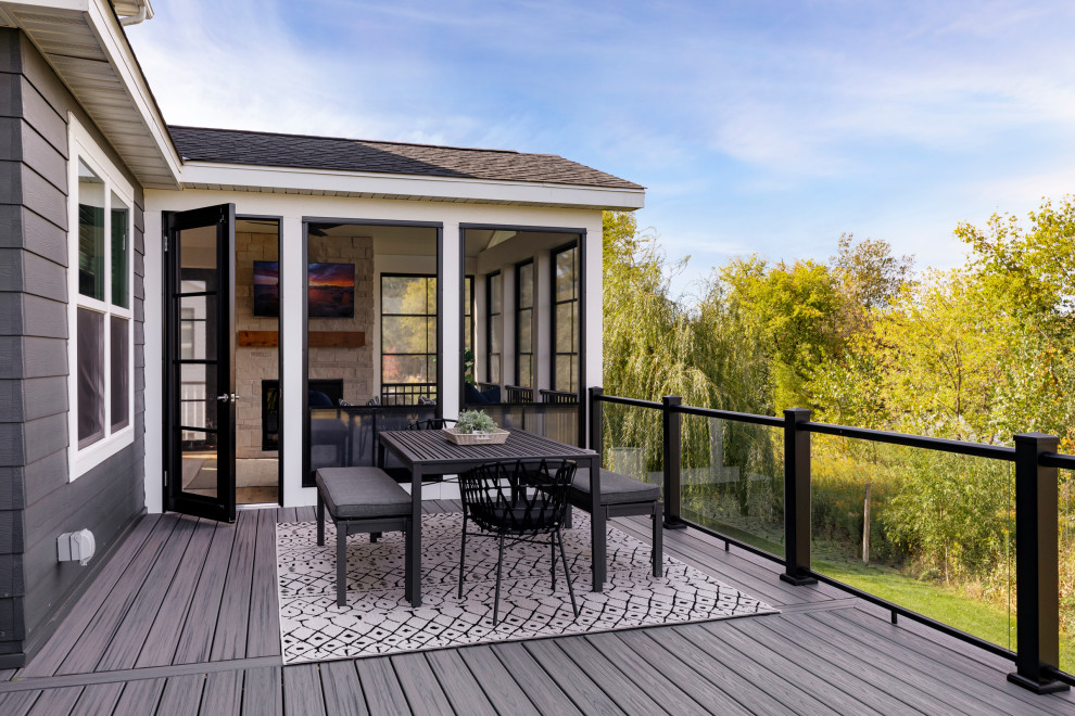 Cette image montre un grand porche d'entrée de maison arrière avec une moustiquaire, une extension de toiture et un garde-corps en verre.