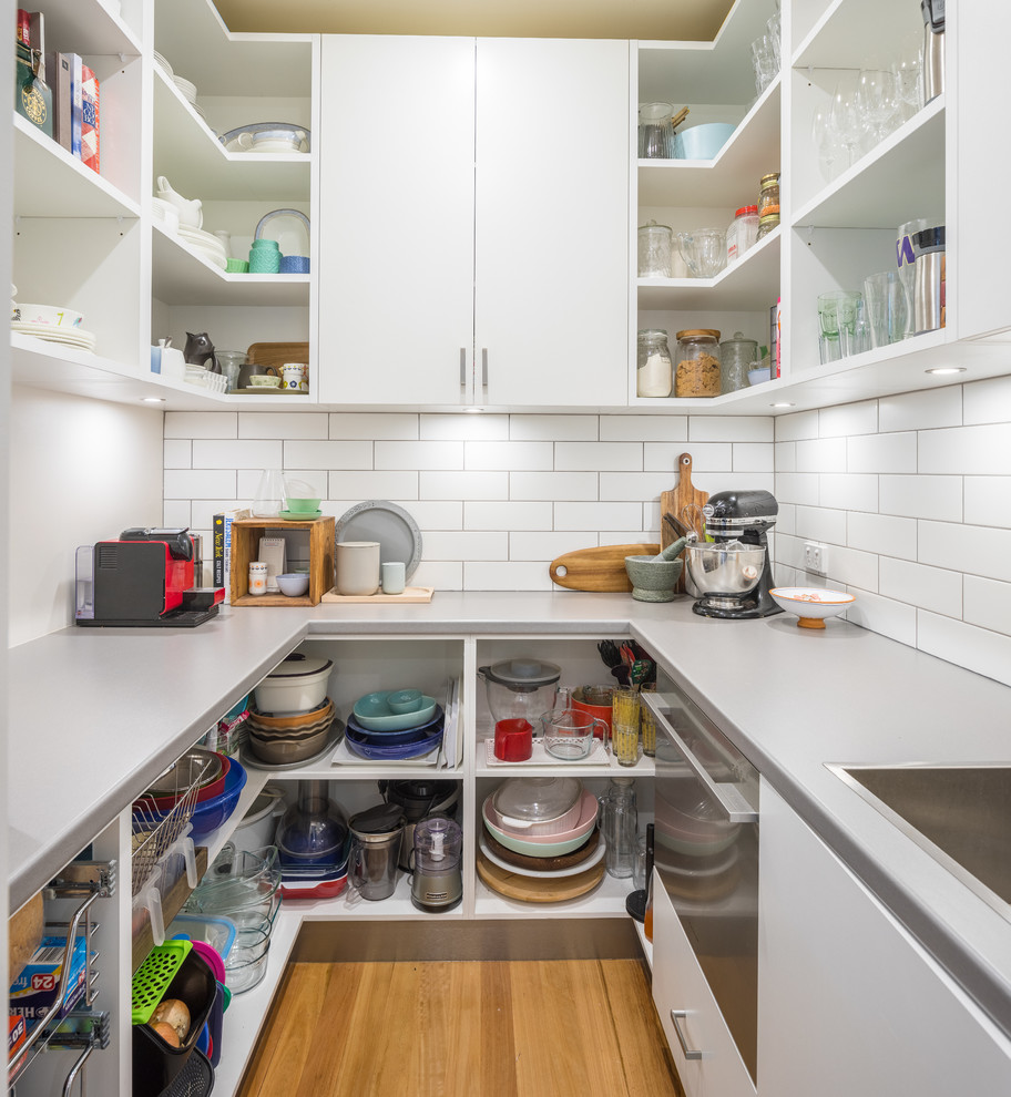 This is an example of a transitional kitchen in Perth with a drop-in sink, open cabinets, white cabinets, laminate benchtops, white splashback, subway tile splashback and grey benchtop.