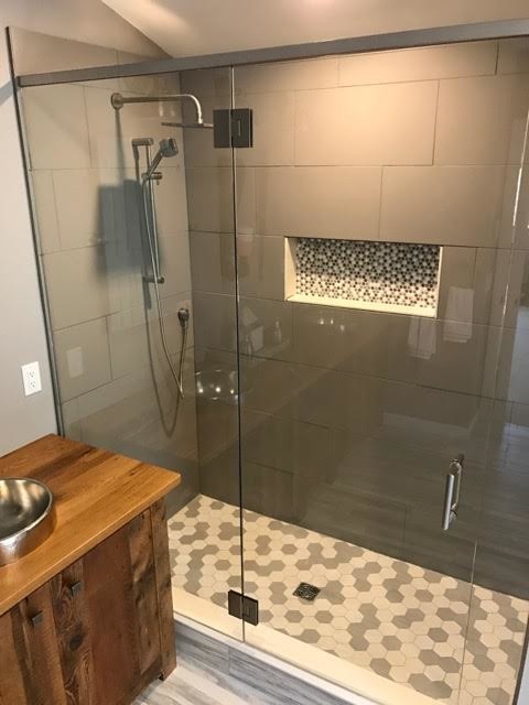 Mid-sized country master bathroom in Portland Maine with dark wood cabinets, a freestanding tub, an alcove shower, gray tile, porcelain tile, grey walls, a vessel sink, wood benchtops and an open shower.