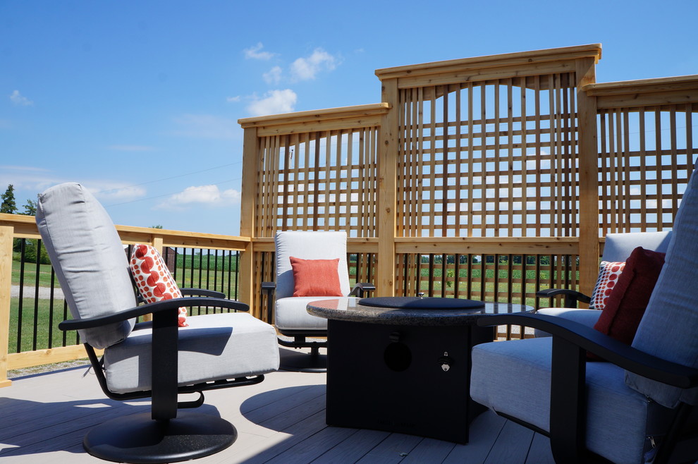 Example of a large transitional backyard deck design in Toronto with a fire pit and no cover