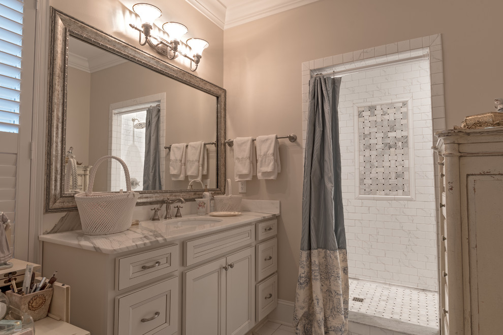 Example of a mid-sized transitional master gray tile, multicolored tile, white tile and stone tile alcove shower design with recessed-panel cabinets, white cabinets, beige walls, an undermount sink and marble countertops