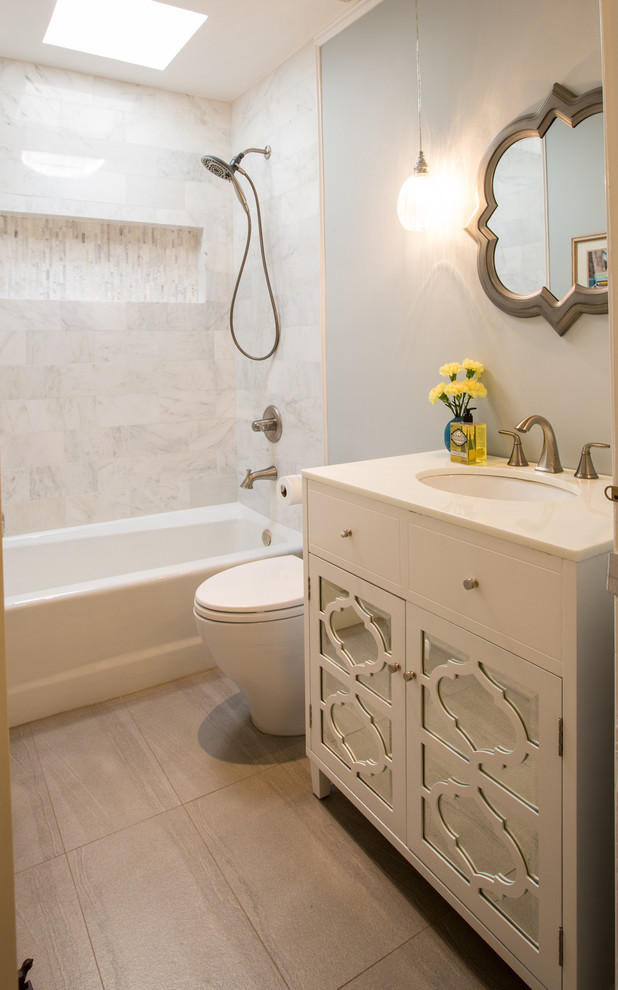 Small transitional bathroom in Los Angeles with glass-front cabinets, white cabinets, an alcove tub, an alcove shower, a one-piece toilet, white tile, stone tile, grey walls, porcelain floors, an undermount sink and quartzite benchtops.