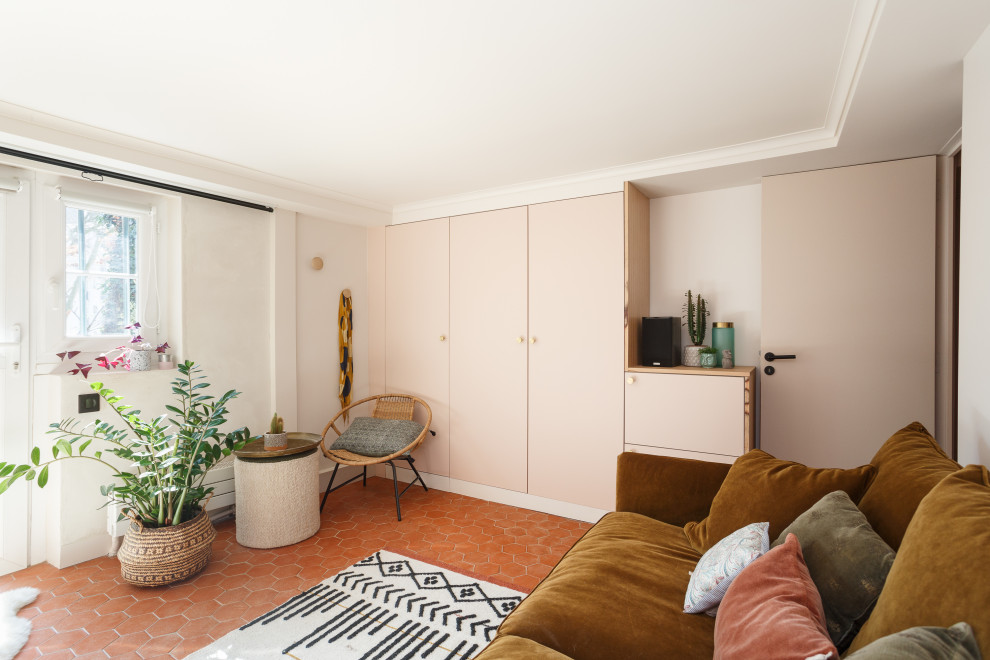 Modelo de despacho mediterráneo de tamaño medio con paredes rosas, suelo de baldosas de terracota, escritorio empotrado y suelo rojo