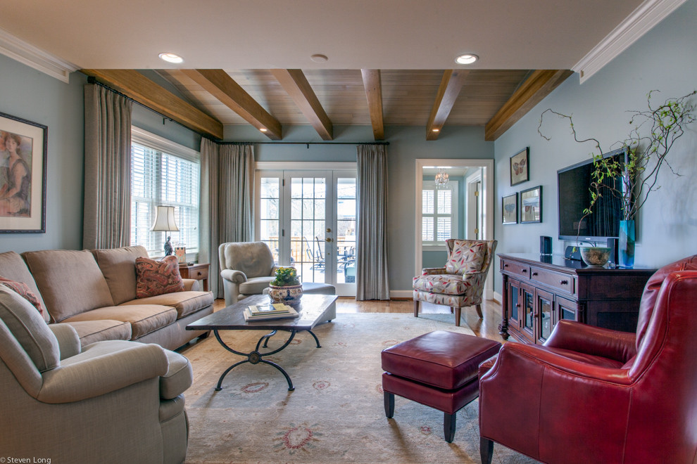 Photo of a mid-sized traditional enclosed family room in Nashville with blue walls, medium hardwood floors, a wall-mounted tv and no fireplace.