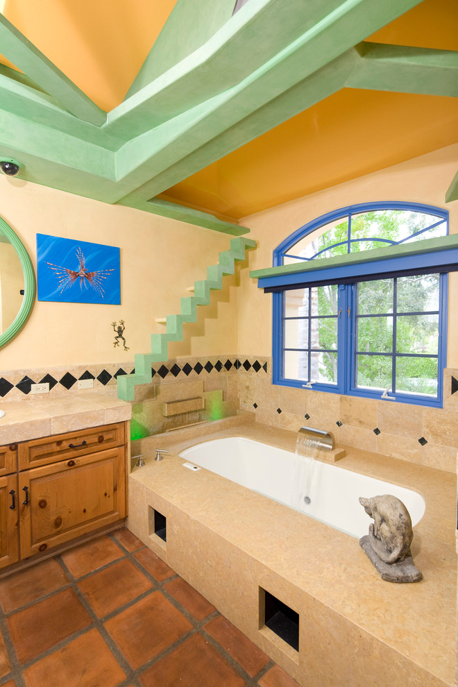 Photo of an eclectic bathroom in Santa Barbara with shaker cabinets, medium wood cabinets, a hot tub, beige tile, stone tile, beige walls and terra-cotta floors.