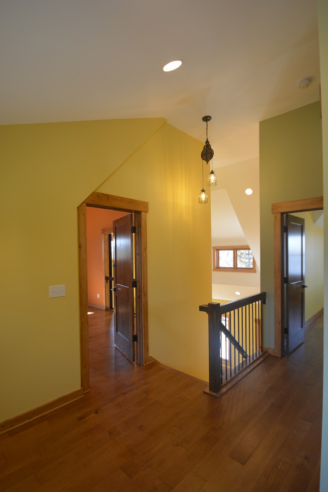 This is an example of a mid-sized arts and crafts hallway in Milwaukee with multi-coloured walls, medium hardwood floors and brown floor.