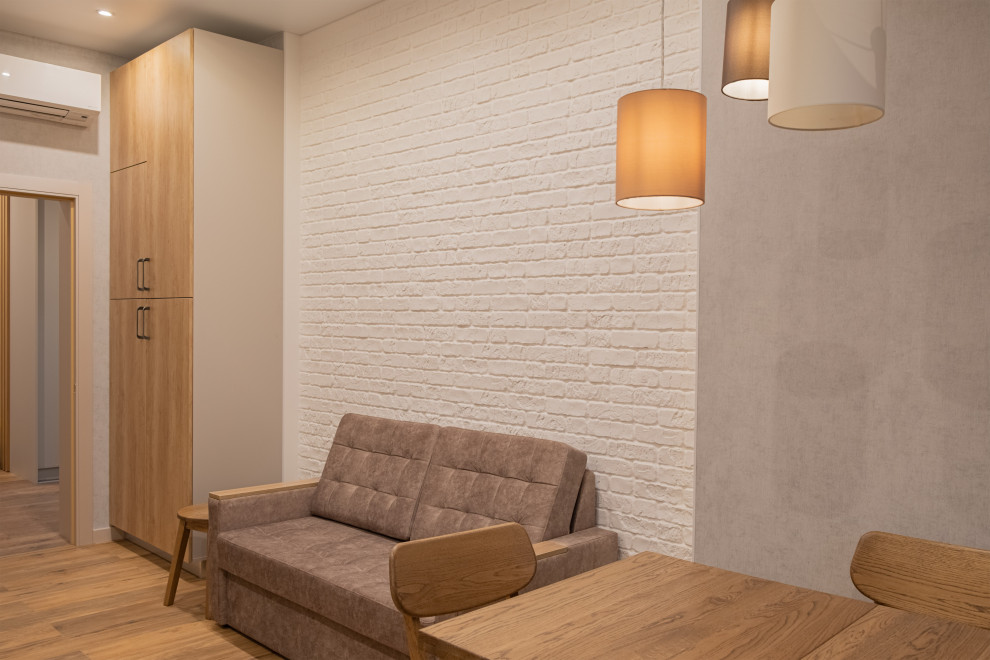 Cette image montre une salle à manger ouverte sur la cuisine design de taille moyenne avec un mur beige, sol en stratifié, aucune cheminée, un sol marron et du papier peint.