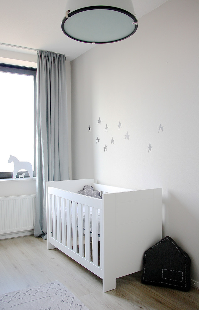 Scandinavian gender-neutral nursery in Amsterdam with white walls, light hardwood floors and beige floor.