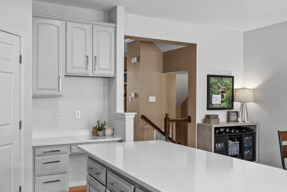 Transitional dark wood floor eat-in kitchen photo with a double-bowl sink, gray cabinets, quartz countertops, stainless steel appliances, an island and white countertops