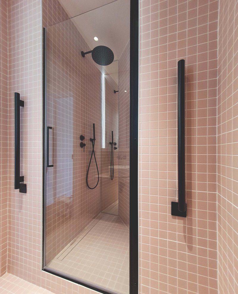 Idéer för små funkis en-suite badrum, med luckor med profilerade fronter, en kantlös dusch, en vägghängd toalettstol, rosa kakel, cementkakel, mosaikgolv, ett konsol handfat, kaklad bänkskiva, rosa golv och dusch med gångjärnsdörr