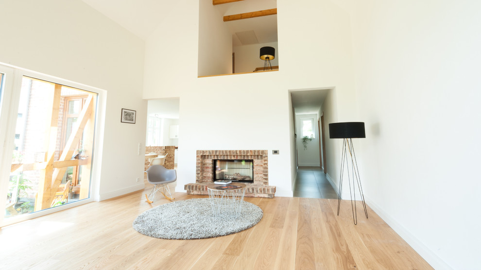 This is an example of a large contemporary living room in Berlin with white walls and light hardwood floors.