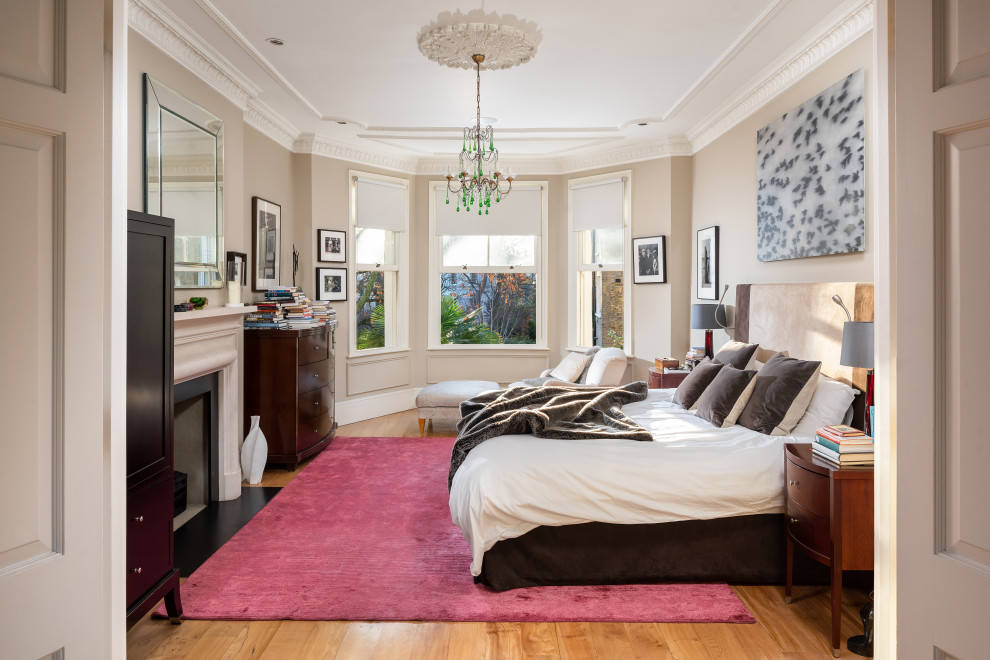 Large bohemian master bedroom in London with beige walls and medium hardwood flooring.