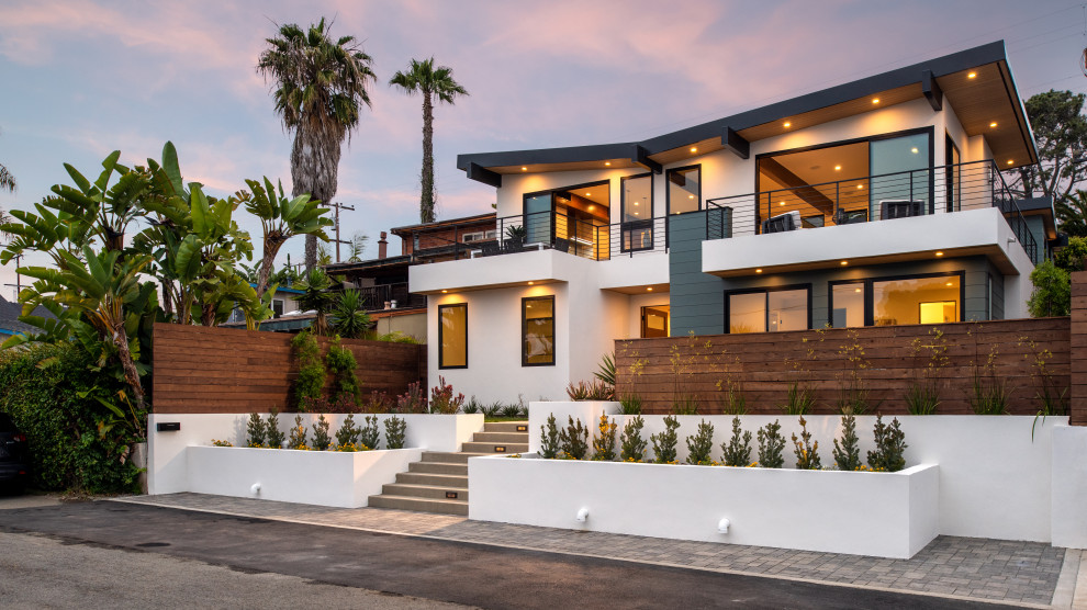 Large modern split-level green house exterior in San Diego with concrete fiberboard siding, a shed roof and a metal roof.