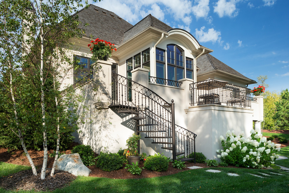 Photo of a large traditional two-storey stucco white house exterior in Minneapolis with a shingle roof.