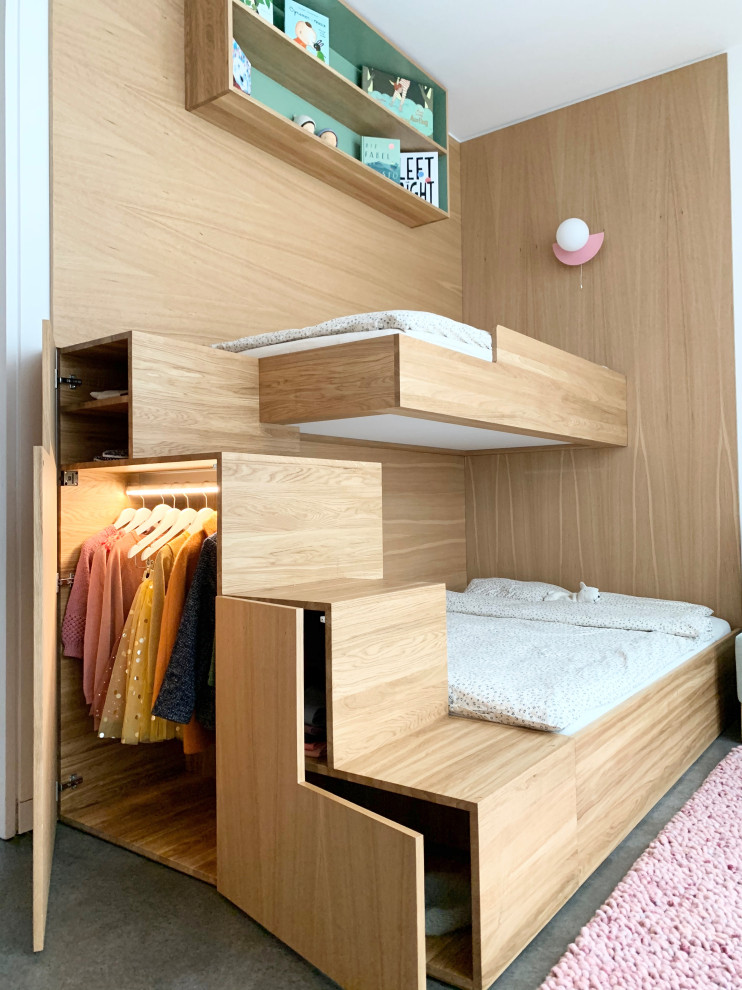 Photo of a small contemporary kids' bedroom for girls in Berlin with white walls, concrete flooring, grey floors and wood walls.