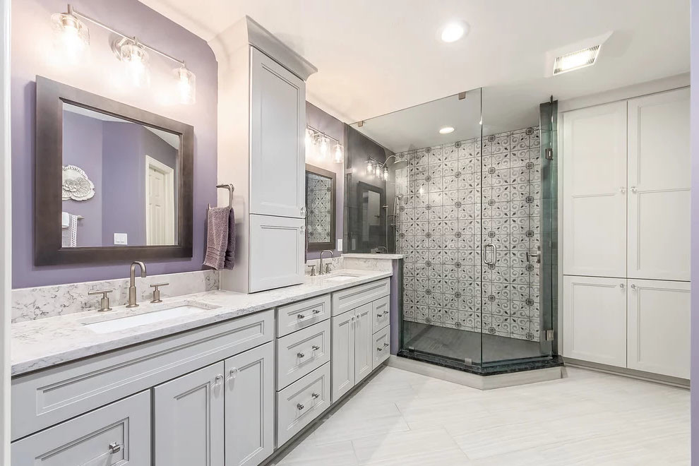 Photo of a large transitional master bathroom in DC Metro with flat-panel cabinets, white cabinets, a freestanding tub, a corner shower, a two-piece toilet, multi-coloured tile, ceramic tile, purple walls, ceramic floors, a drop-in sink, engineered quartz benchtops, grey floor, a shower curtain and white benchtops.