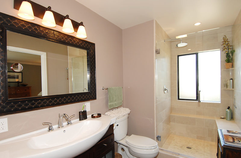 Inspiration for a mid-sized traditional master bathroom in San Francisco with furniture-like cabinets, dark wood cabinets, an alcove shower, stone tile, pink walls, an integrated sink, a one-piece toilet, beige tile, solid surface benchtops and a hinged shower door.