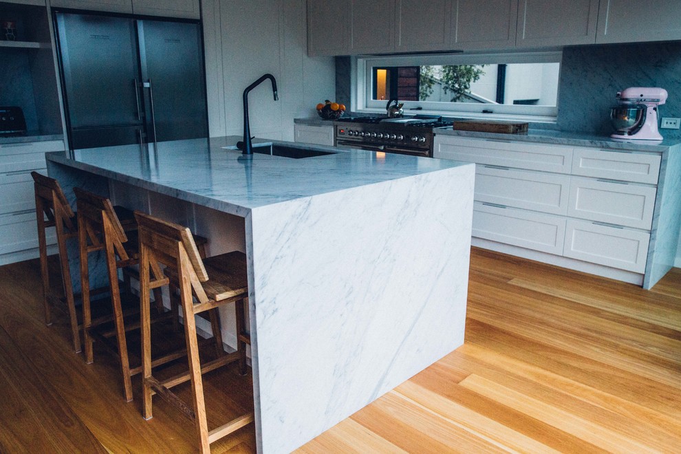 Inspiration for a contemporary l-shaped open plan kitchen in Sydney with white cabinets, marble benchtops, grey splashback, stone slab splashback, stainless steel appliances, medium hardwood floors, with island, an undermount sink and recessed-panel cabinets.
