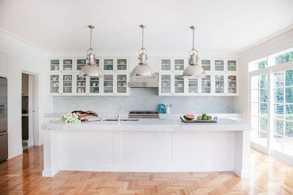 Inspiration for a mid-sized transitional galley eat-in kitchen in Sydney with an undermount sink, glass-front cabinets, white cabinets, marble benchtops, grey splashback, glass tile splashback, stainless steel appliances, medium hardwood floors and with island.