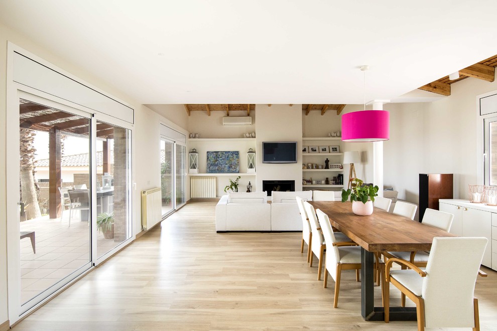 Contemporary open plan dining in Barcelona with light hardwood floors, a standard fireplace, a plaster fireplace surround, beige walls and beige floor.