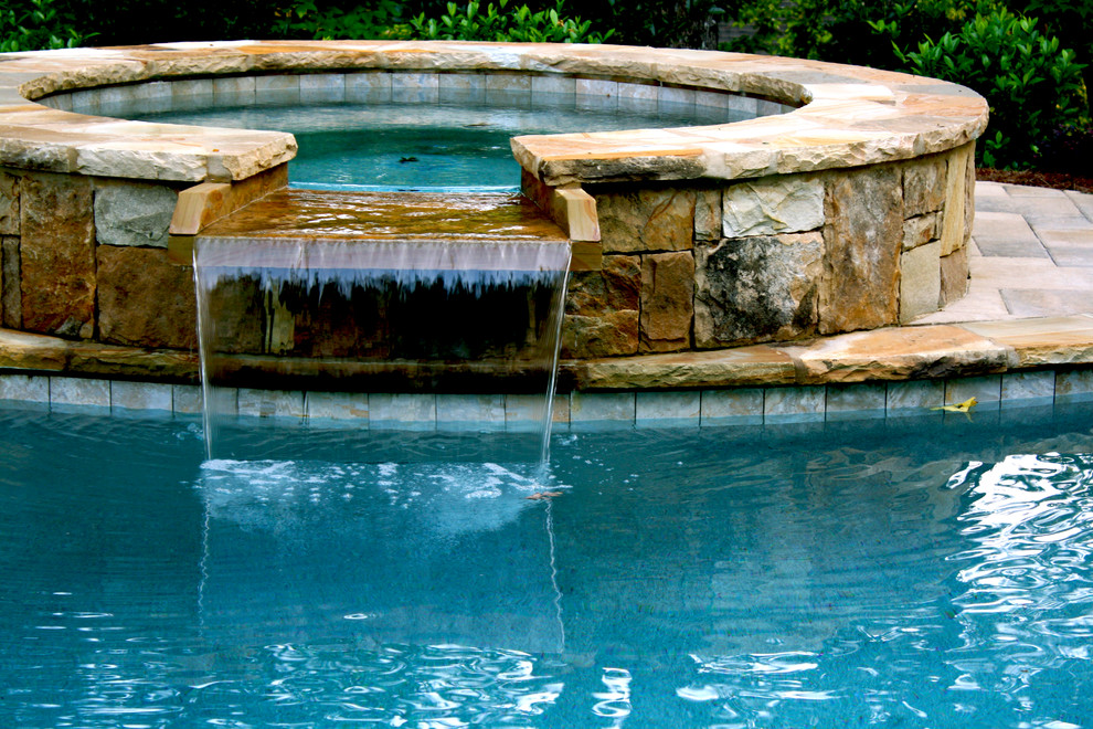 This is an example of a mid-sized traditional backyard kidney-shaped lap pool in Atlanta with a hot tub and brick pavers.