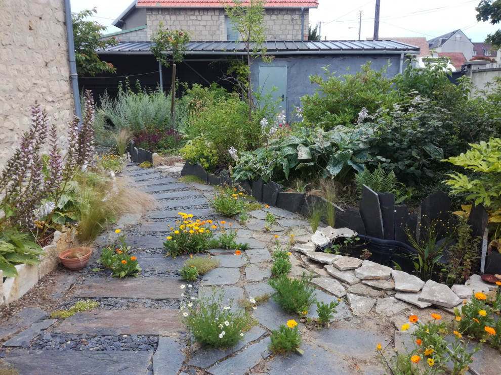 Inspiration for a small modern side yard garden in Le Havre with with rock feature and mulch.