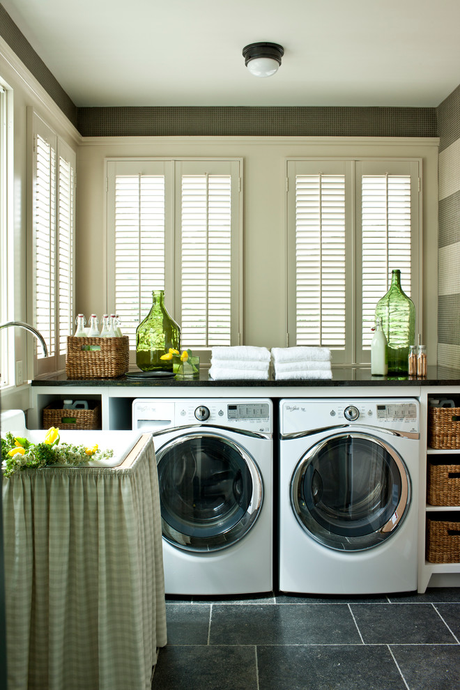 This is an example of a large country laundry room in Nashville with white cabinets, onyx benchtops, slate floors, a side-by-side washer and dryer, open cabinets, black benchtop, a drop-in sink and grey walls.