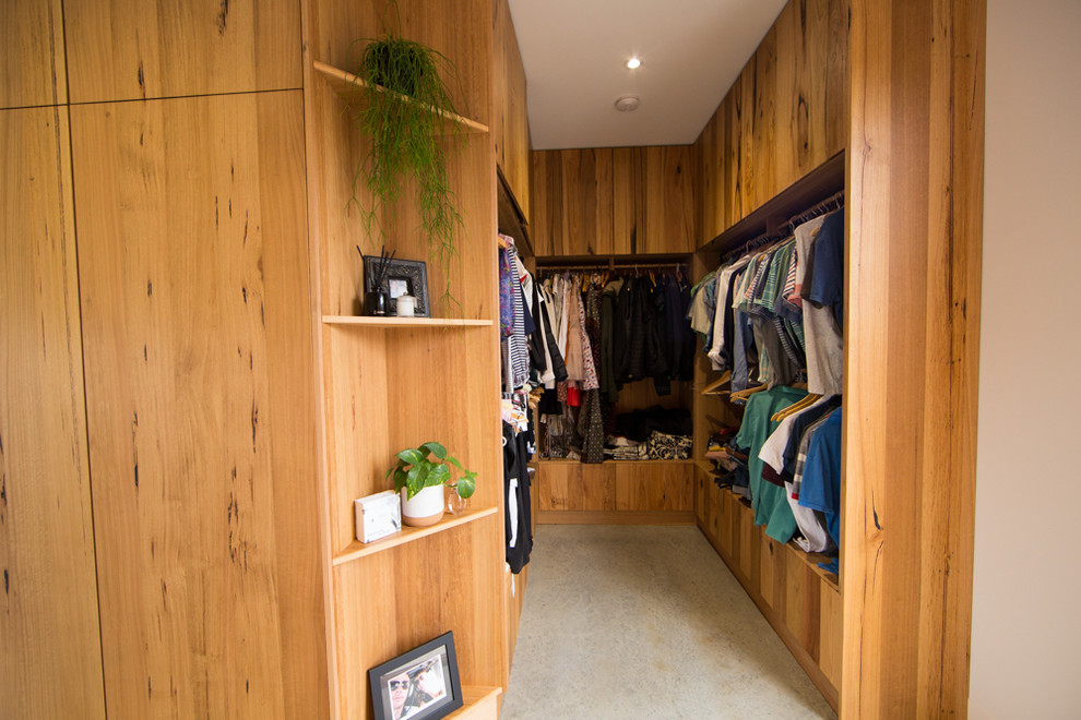 Large contemporary walk-in wardrobe in Geelong with medium wood cabinets, concrete floors and grey floor.