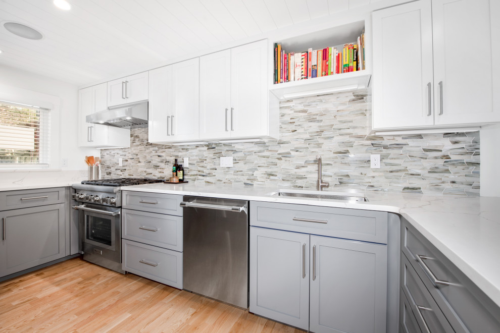 Design ideas for a small transitional u-shaped open plan kitchen in Boston with an undermount sink, shaker cabinets, white cabinets, quartz benchtops, grey splashback, glass tile splashback, stainless steel appliances, medium hardwood floors, a peninsula, brown floor, white benchtop and exposed beam.
