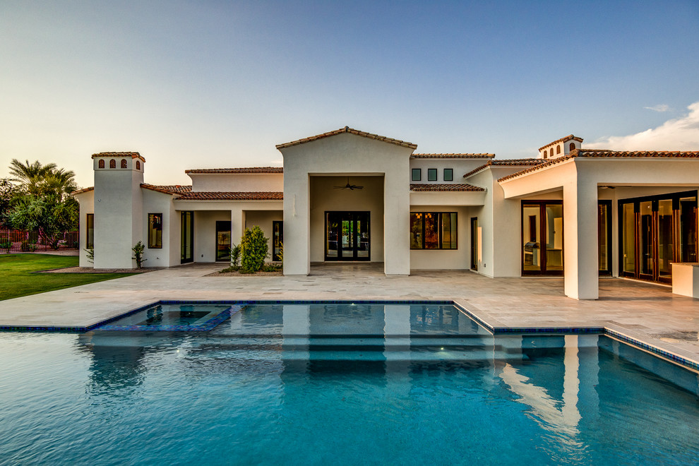Expansive transitional backyard rectangular infinity pool in Phoenix with a hot tub and tile.