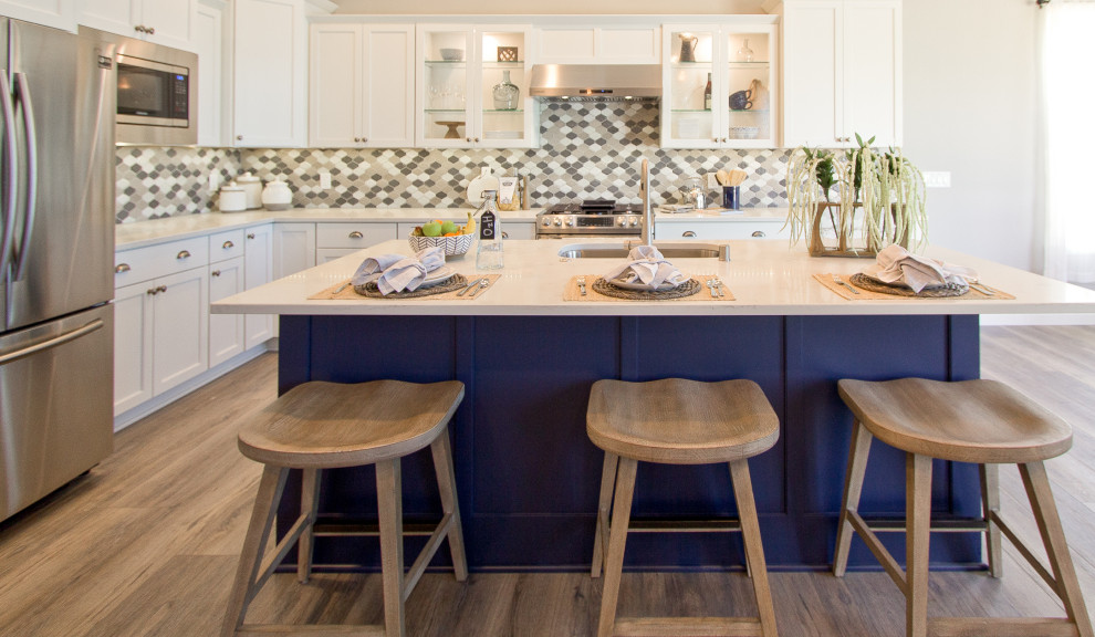 Eat-in kitchen - transitional l-shaped brown floor, vaulted ceiling and vinyl floor eat-in kitchen idea with an undermount sink, recessed-panel cabinets, quartz countertops, multicolored backsplash, mosaic tile backsplash, stainless steel appliances, an island and white countertops