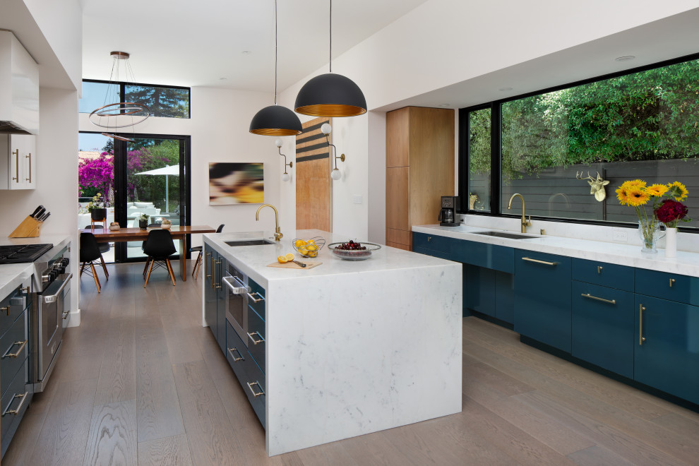 Photo of a large midcentury eat-in kitchen in San Diego with an undermount sink, flat-panel cabinets, green cabinets, marble benchtops, white splashback, ceramic splashback, stainless steel appliances, medium hardwood floors, with island, grey floor, white benchtop and vaulted.