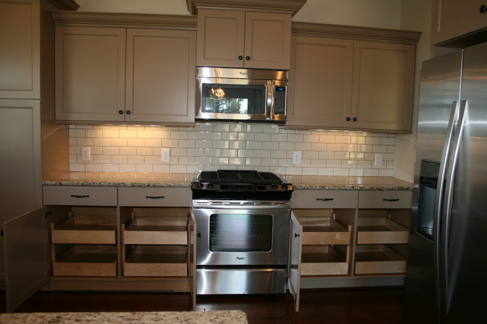 Kitchen - mid-sized rustic dark wood floor kitchen idea in Omaha with an undermount sink, shaker cabinets, beige cabinets, granite countertops, white backsplash, subway tile backsplash, stainless steel appliances and an island