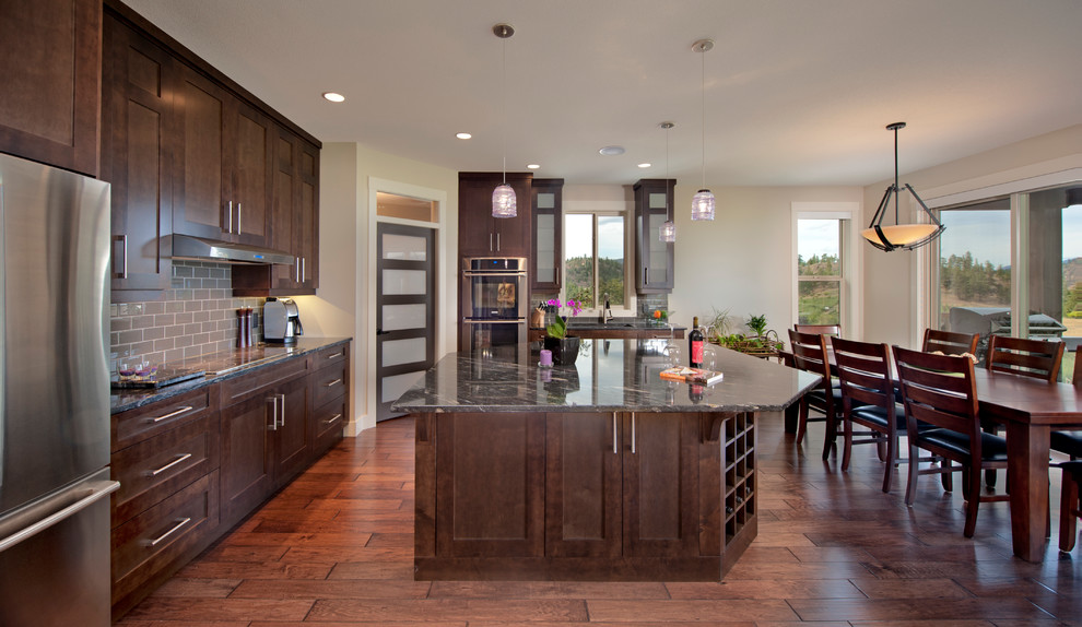 Inspiration for a large arts and crafts l-shaped open plan kitchen in Vancouver with a drop-in sink, dark wood cabinets, granite benchtops, stainless steel appliances, dark hardwood floors and with island.