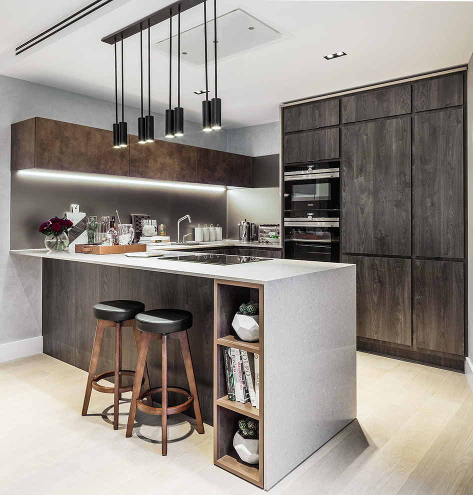 Contemporary u-shaped kitchen in Austin with flat-panel cabinets, dark wood cabinets, black appliances, light hardwood floors, a peninsula and beige floor.